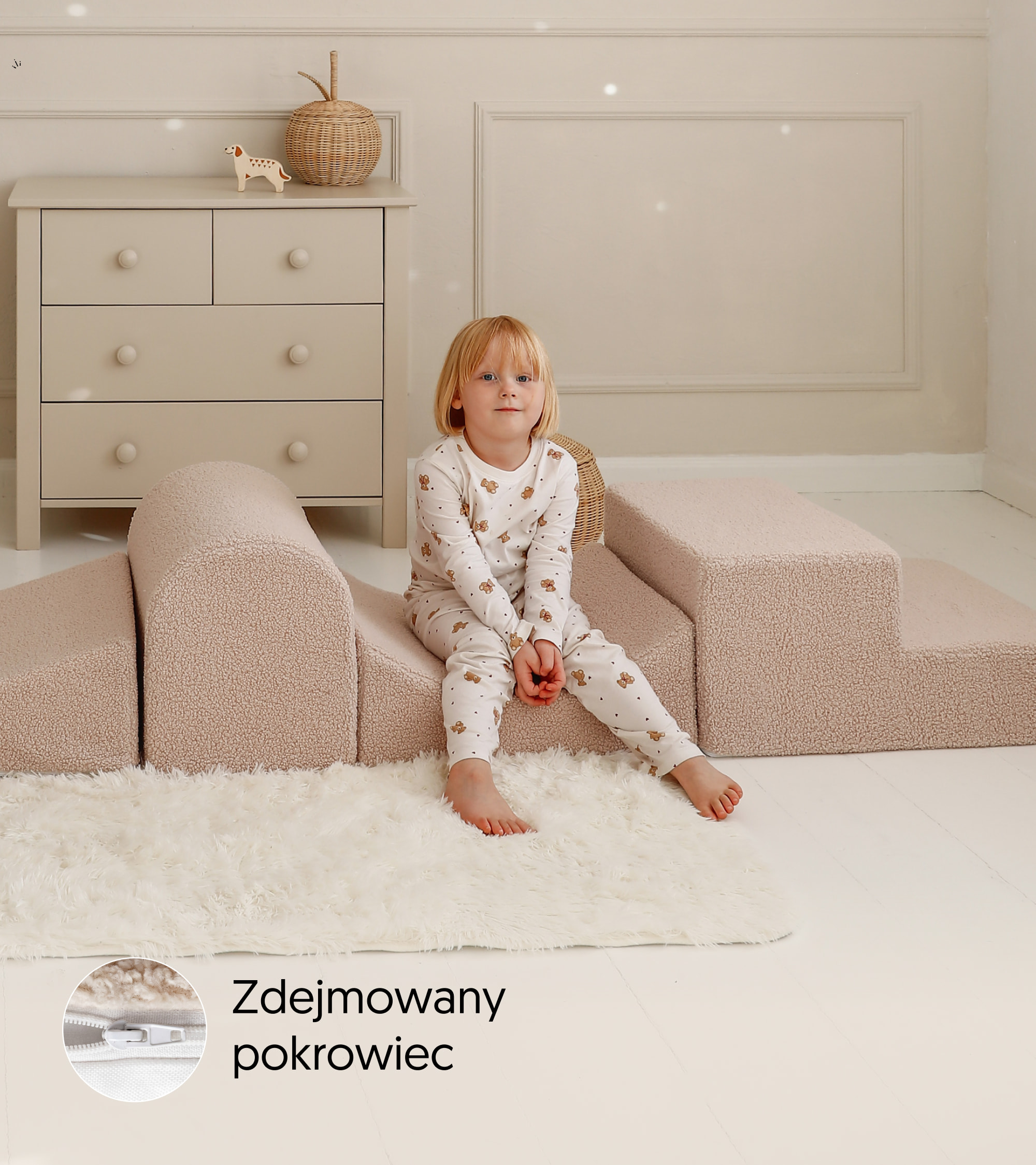Dziewczynka siedzi między elementami Alto Teddy Latte; poniżej widoczna jest plakietka zdejmowanego pokrowca z detalem zamka.