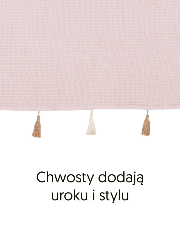 Brzeg poncza z bawełny waflowej w kolorze różowym i ozdobne chwosty, z podpisem „Chwosty dodają uroku i stylu”.